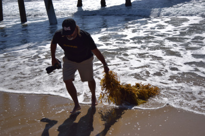 Broza poses underneath the Hermosa Beach pier where he takes his bike, camera, and a cup of coffee every morning to photograph the smooth morning break.