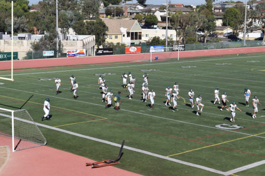 The Mira Costa Junior Varsity football team warms up their legs before practice on Wednesday.