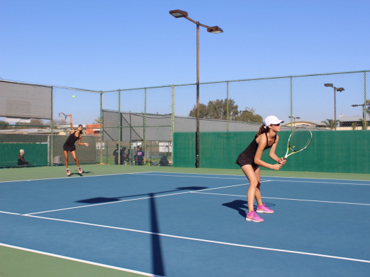 Olga serves the ball as Audrey stands ready to react to the other team’s response.