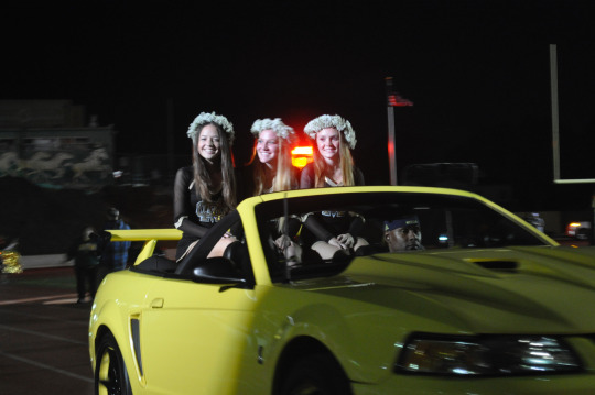 Three members of the Mira Costa High School dance team ride by the crowd before the homecoming court members go by. 