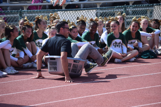 English teacher, Mr. Chow participates in the Pep Rally, competing against the four other grade levels, and has to sit and slide his basket across the track.