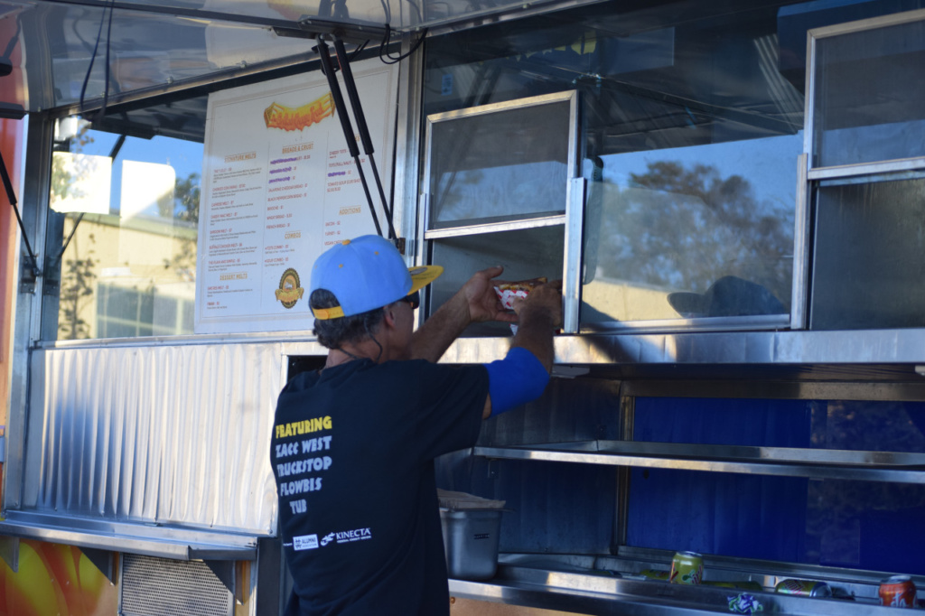Mr. Mckeegan is picking up his order at the Grilled Cheese truck on Friday at Costapalooza. There were food trucks, business booths and a live band playing all located in the Mustang Mall.