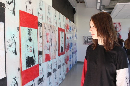 Sophomore Devon McKnight looks at junior Mazzy MacGregor’s art gallery in room 60 at lunch on Wednesday. Mazzy’s art gallery filled with street art opened today and will be up until next Wednesday.