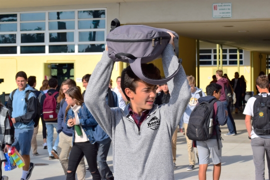 Junior Alex DeSousa shields his head with his backpack to protect himself from seagull droppings as he walks through the Mustang Mall after nutrition. Backpacks, hoods, and textbooks have all proven effective in fighting the dangers from above.