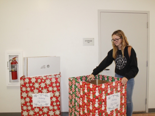 Sophomore Elle Webber puts a gift in the Christmas toy drive donation box at the beginning of lunch. The drive started around the beginning of December and has already collected hundreds of items for people in need.