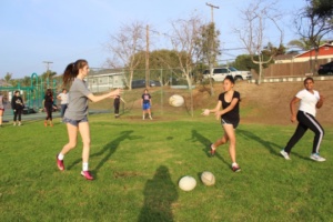 Girls Rugby players practice their passing by rotating the ball down a line of four girls.