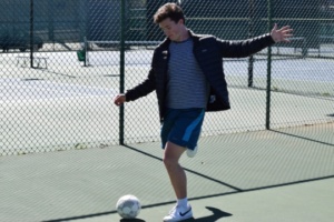 Senior Carson Phillips kicks a soccer ball amidst a game of futsal during lunch at the tennis courts on Thursday. The futsal tournament began on Wednesday, February 22, and will continue into the following week.