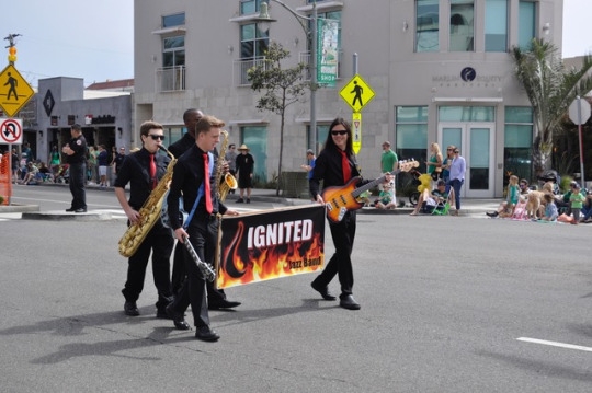 The “Ignited” jazz band walks the parade while holding their instruments and a poster with their band name on it. This jazz band includes some of the costa students that participated in the parade.  