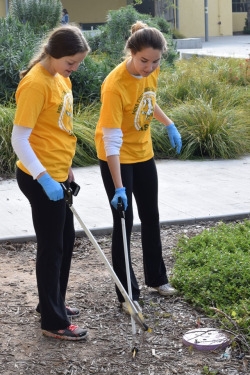  (Middle) Senior ASB members Rose Darcy (left) and Emily Angiolini (right) pick up trash in the Mustang Mall outside the ASB room. Students and staff used tools to ease the process of cleaning the school.