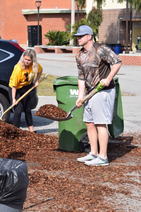 Vice Principal and Athletic Director Jon Shaw shovels wood chips into trashcans to be transported to the Mustang Mall. Mr. Shaw and Dr. Dale both participated in the campus cleanup on Costa Pride Day.