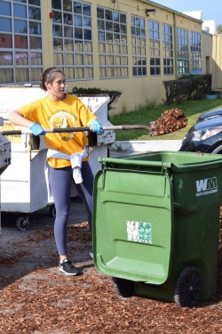Senior ASB member Leah James shovels wood chips into a trash can for another ASB member to take to another part of the Mira Costa campus. The campus cleanup was mainly completed by ASB members, who woke up before 9 AM to help at Costa Pride Day.