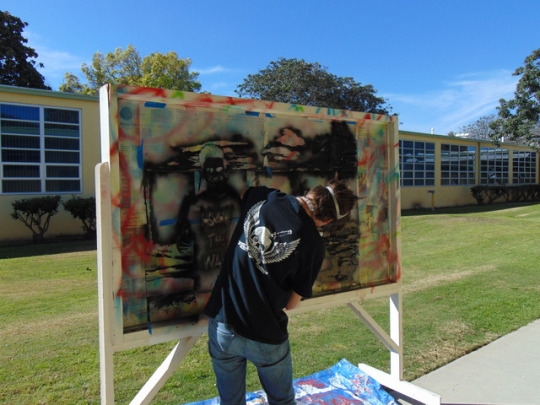 Junior Mazzy Macgreger arranges newspaper lining around his art project as he prepares to spray paint the board. Macgreger plans to title and showcase his work in the spring art show.  