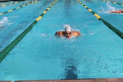Senior Henry Anthony swims the 100 meter butterfly for Varsity on Friday after school at the pool. Anthony got first his event which helped gain more points for Costa. 