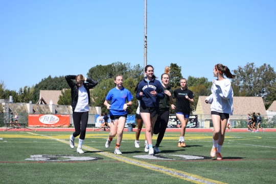 Varsity and JV girls lacrosse players are warming up before practice on Friday. Their warm-up consisted of getting in six different lines, and following each girl in front of them their workout routine.