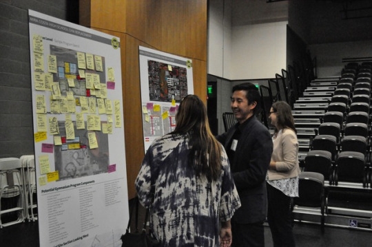 Architect Steve Chung speaks to an attendee about the mapped out plans for the sports facilities. Poster boards were set up around the small theater with information about the architectural plans. 