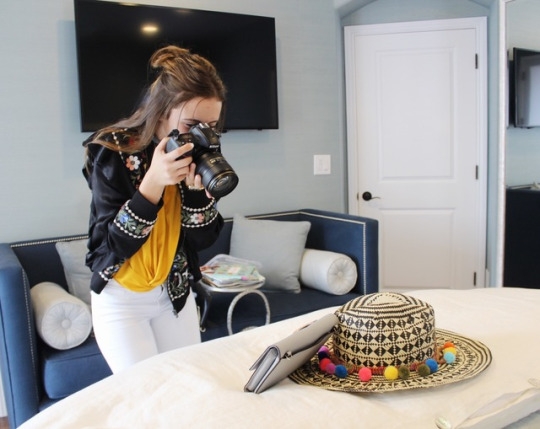 Shirina takes a picture of a hat, glasses, and handbag for her blog. She posted various accessories that go together and match.