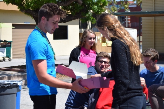 Cunningham continues to pass out donuts during lunch to senior Frances Caflisch. He used this campaign technique as a way to publicize his name in a positive way before elections take place.