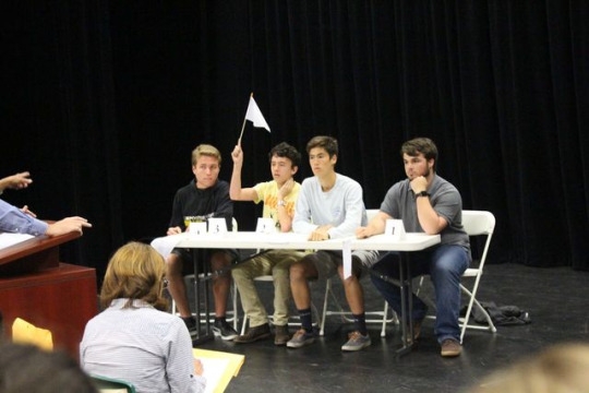 Senior Ben Falley raises his flag during a lightning round at his scholar quiz match in the small theater. Falley’s team lost to three time Scholar Quiz champions, Lu’s team.