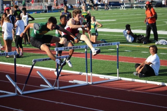 James O, Senior, jumps the hurdles during his 100 meter hurdle race on Saturday. James was neck and neck with his opponents, including senior Eli Bedford until the end of the event. 