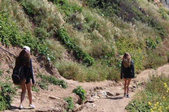 Ettley (left) and Balzer (right) continue their hike down to the beach and tide pools on a steep trail. They walked on opposite sides of the trail to stay safe avoiding the trench in the middle that was formed from all of the rain the previous day.