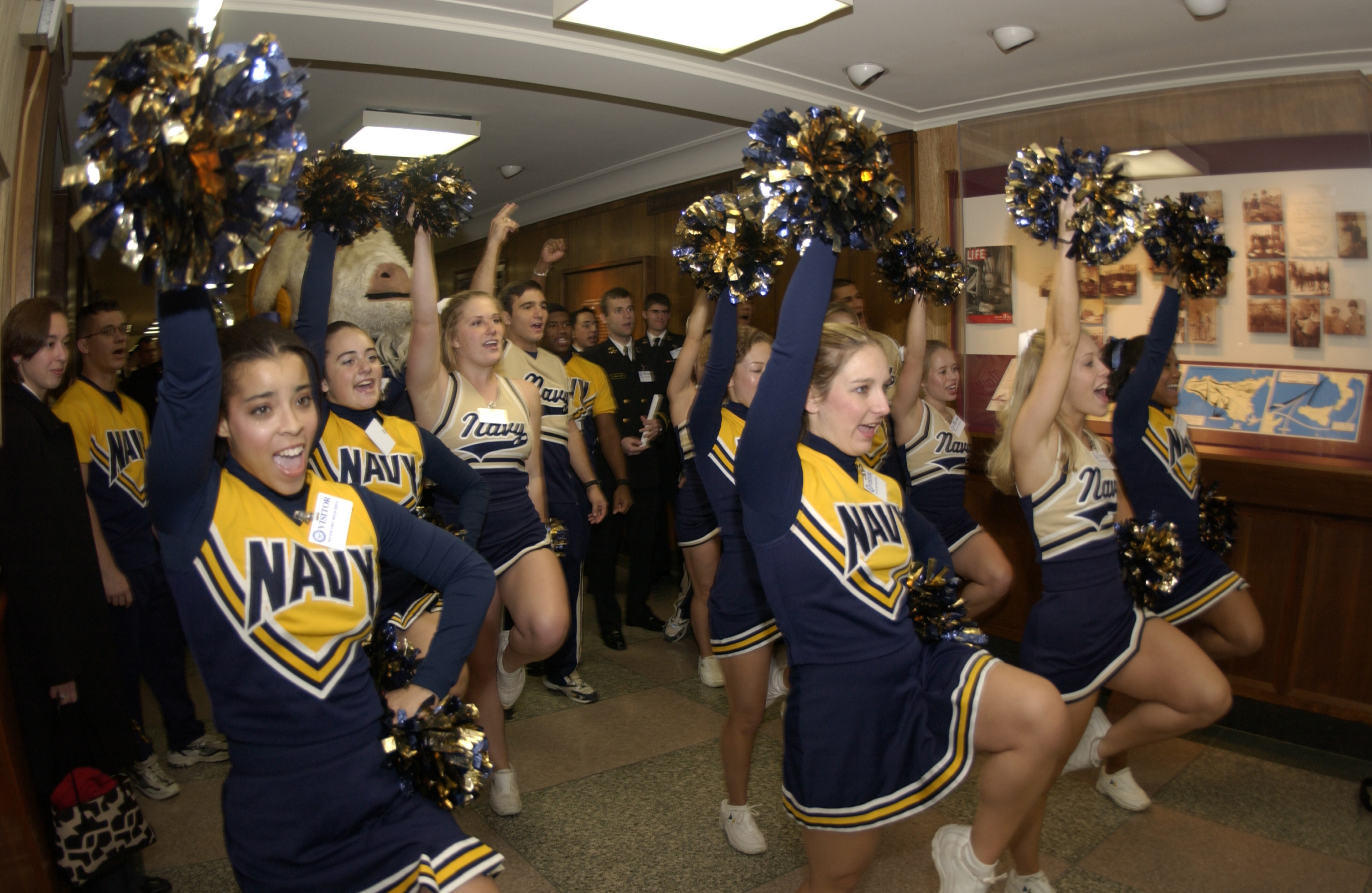 Naval Academy Midshipmen cheerleaders and band members pass through the hal...